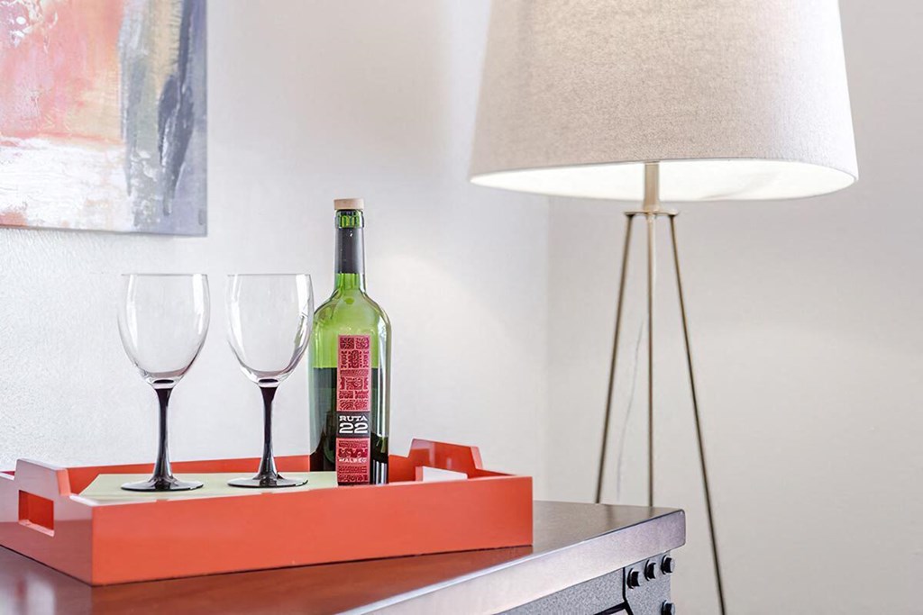 a bottle of wine on a table with glasses and a lamp