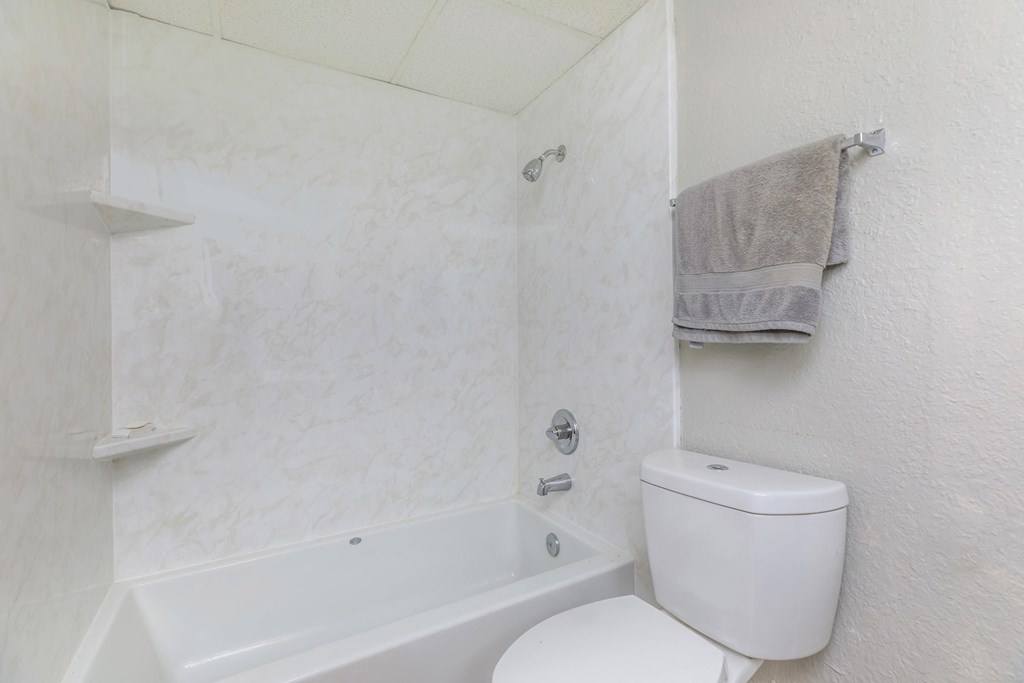 a white bathroom with a white toilet and a bath tub