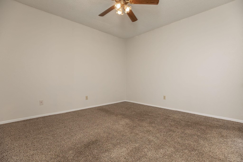 an empty room with carpet and a ceiling fan
