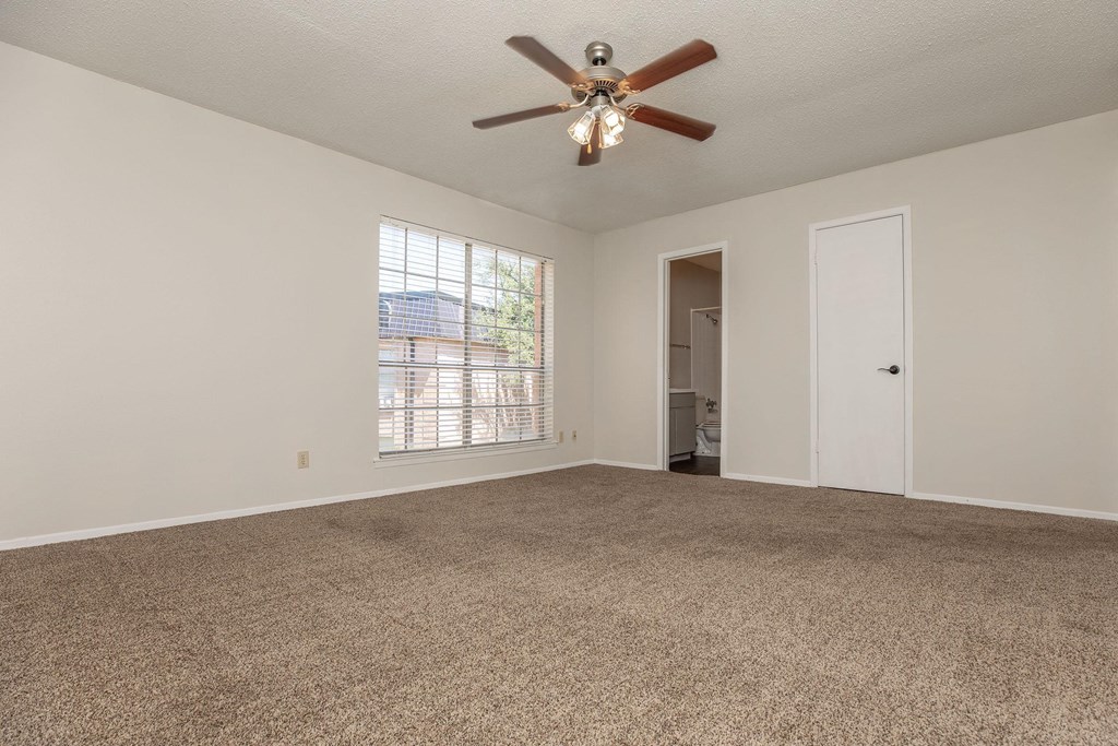 an empty living room with a ceiling fan and a window