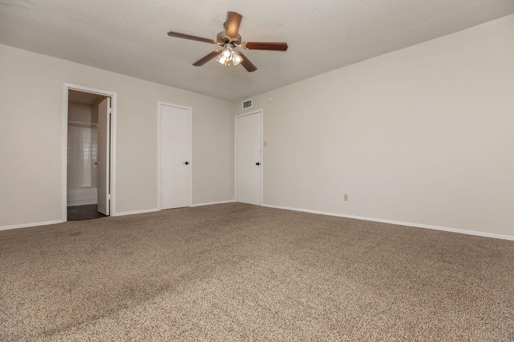 a spacious living room with carpet and a ceiling fan