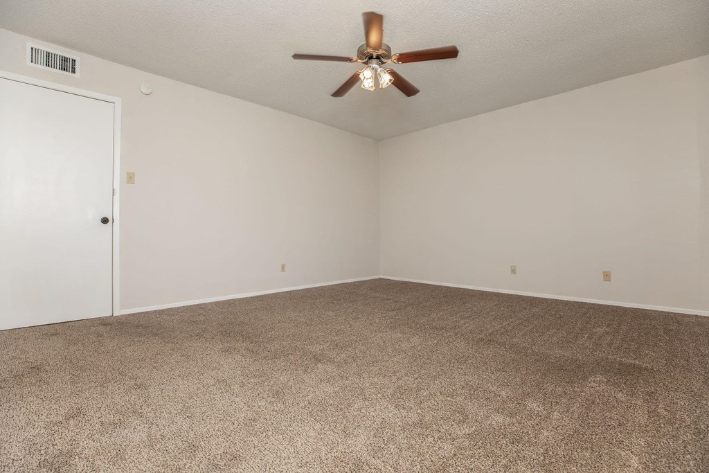 an empty living room with carpet and a ceiling fan