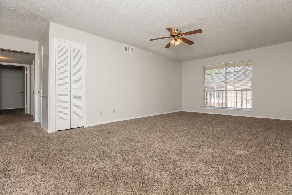 an empty living room with a ceiling fan and a window