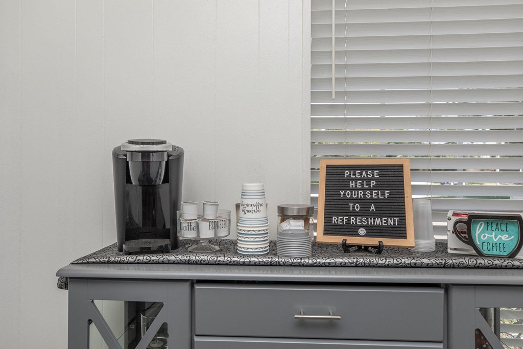 a kitchen counter with a coffee maker and a sign that says praise your self to