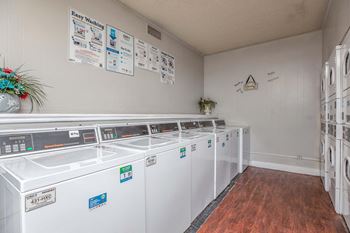 a laundry room with rows of washes and dryer machines