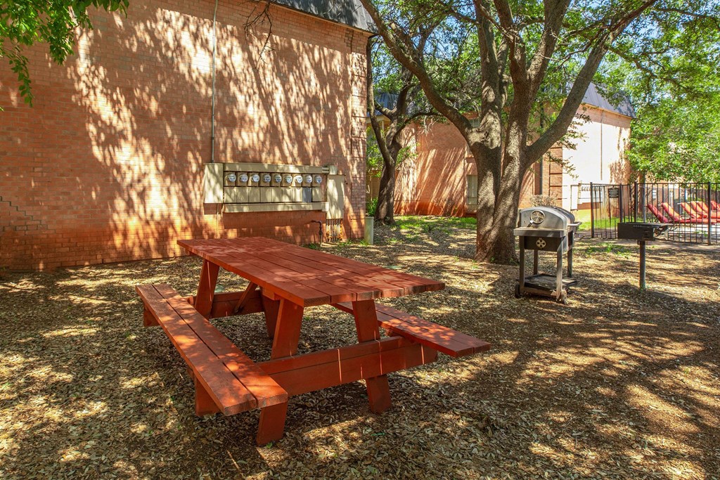 a picnic table in the yard of a building with a grill