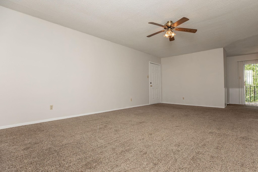 an empty living room with a ceiling fan