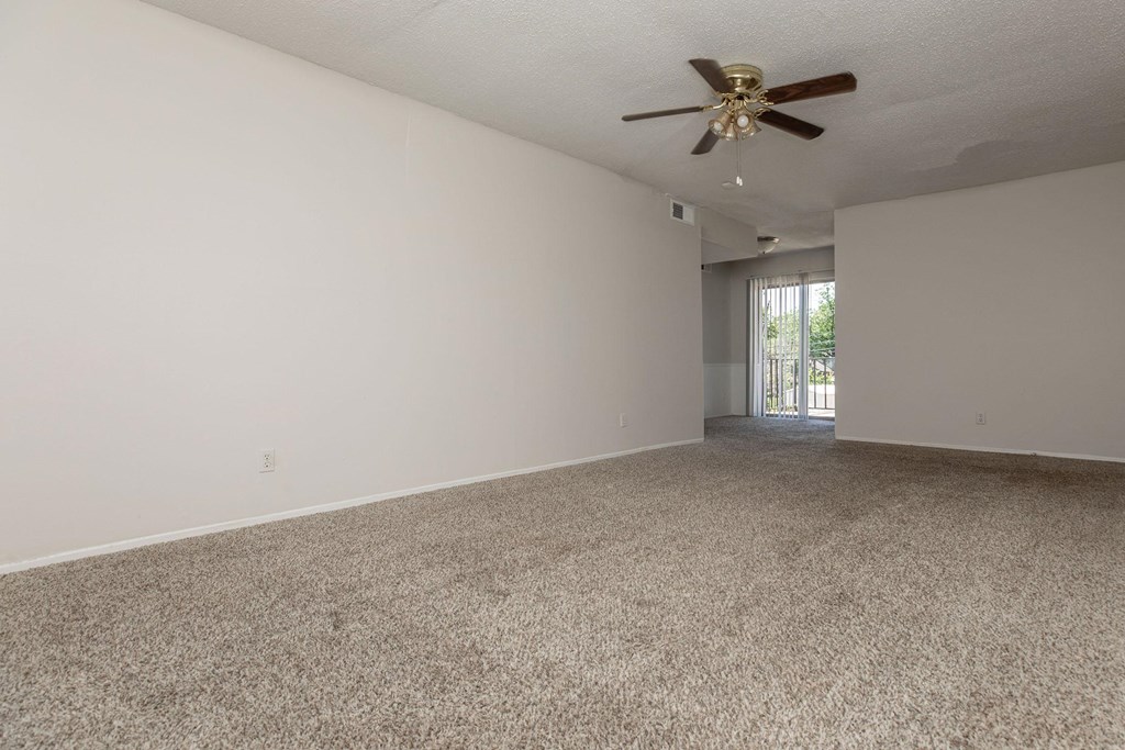 an empty living room with carpet and a ceiling fan
