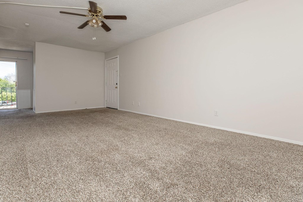 an empty living room with carpet and a ceiling fan