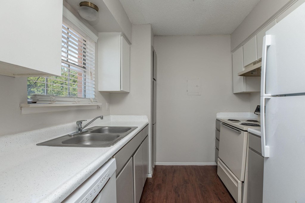 an empty kitchen with white appliances and white cabinets