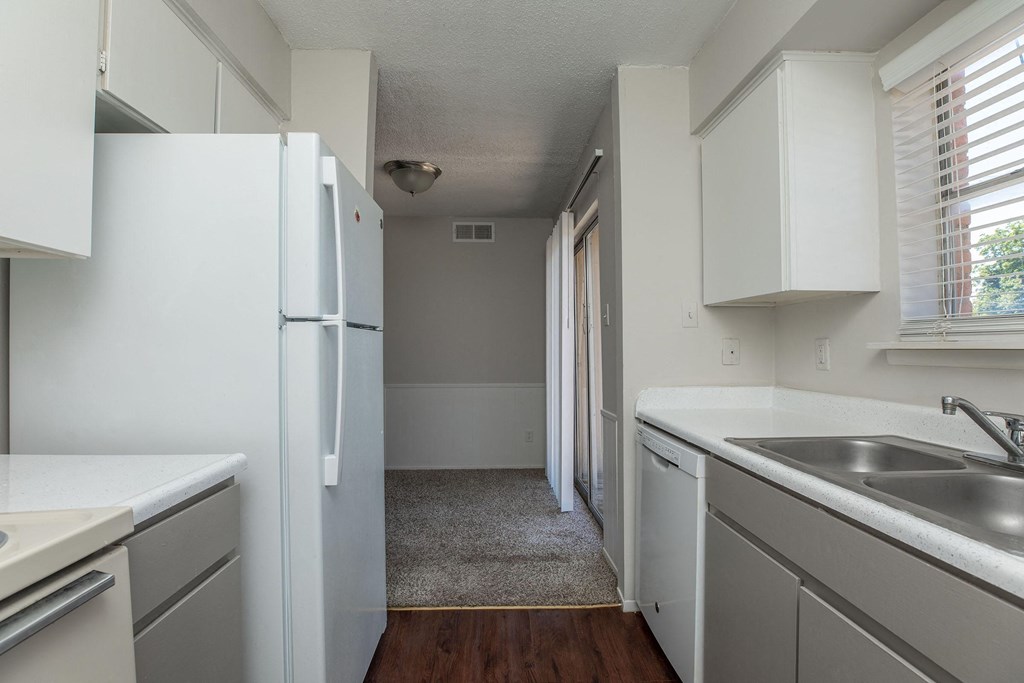 an empty kitchen with white cabinets and a white refrigerator