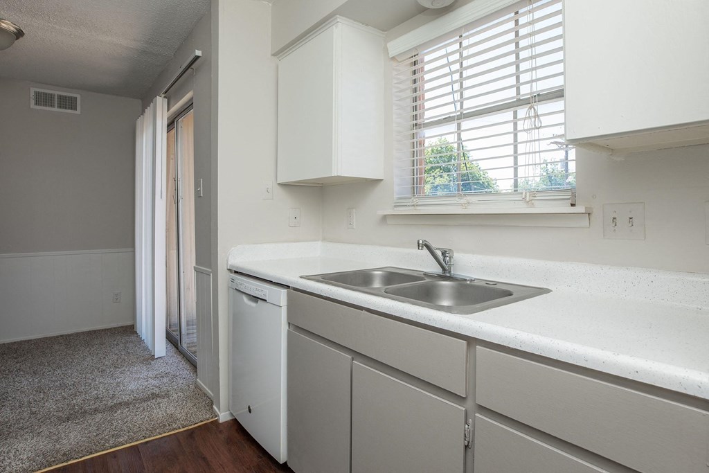 a kitchen with white cabinets and a sink and a window