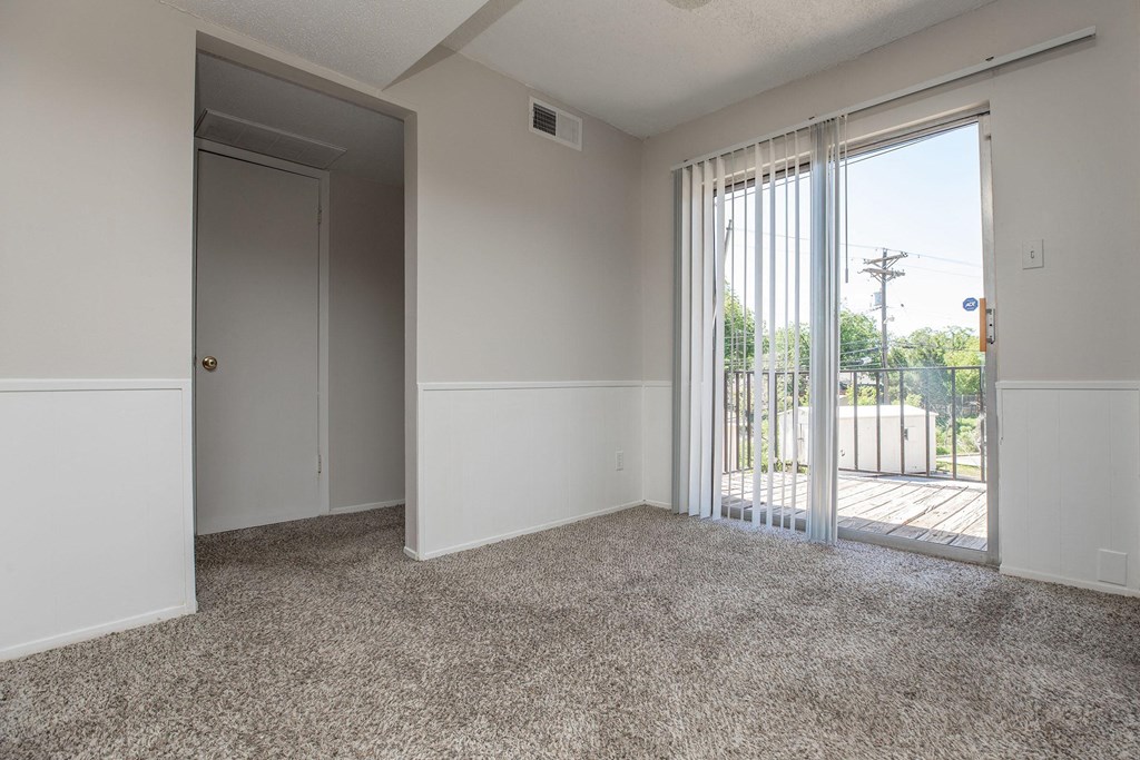 an empty living room with a sliding glass door to a balcony