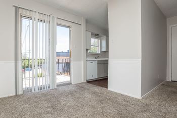 an empty living room with sliding glass doors to a kitchen