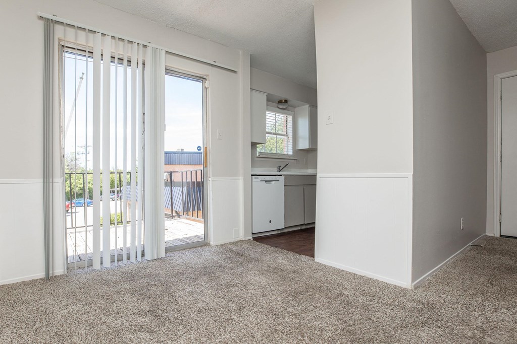 an empty living room with sliding glass doors to a kitchen