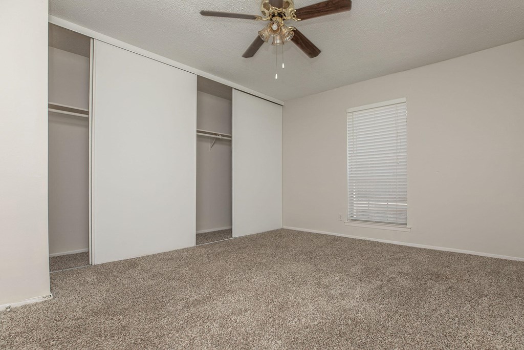 an empty living room with a ceiling fan and a closet