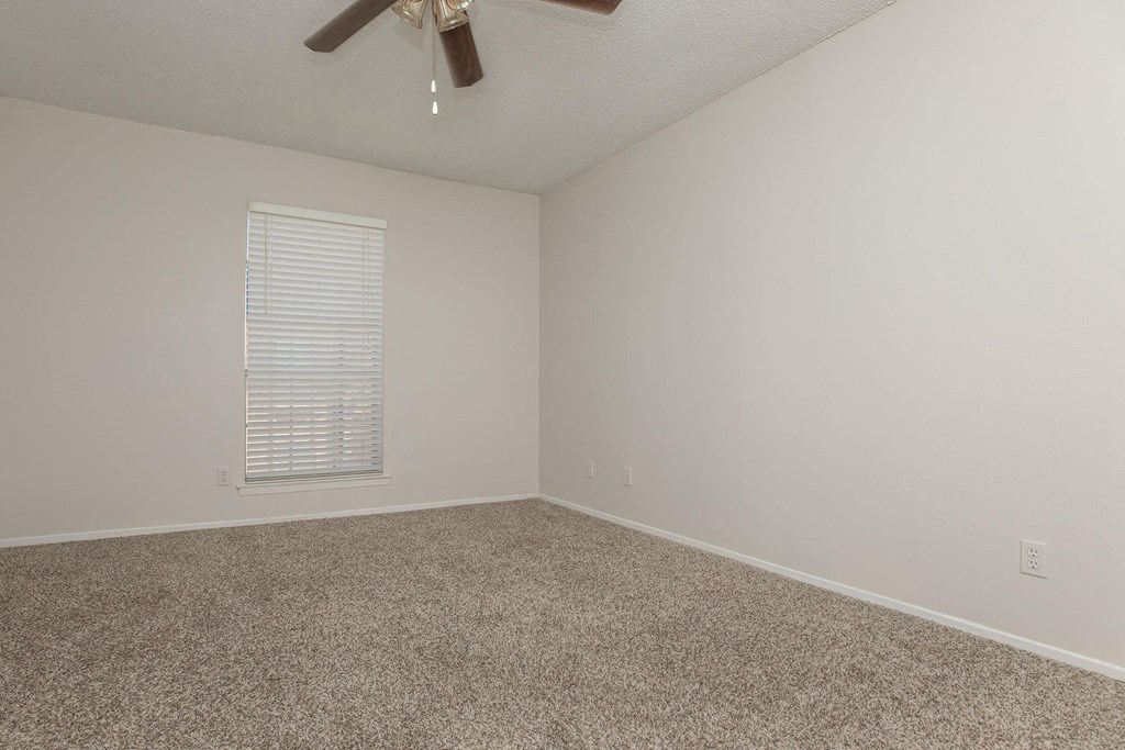 an empty room with carpet and a ceiling fan