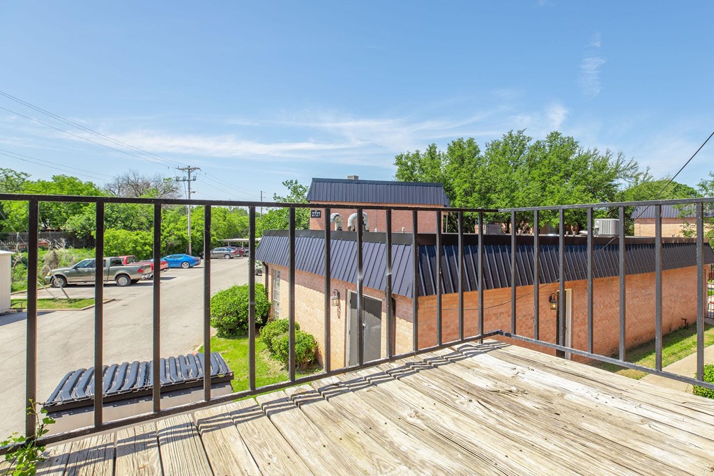 a balcony with a wooden deck and a brick building