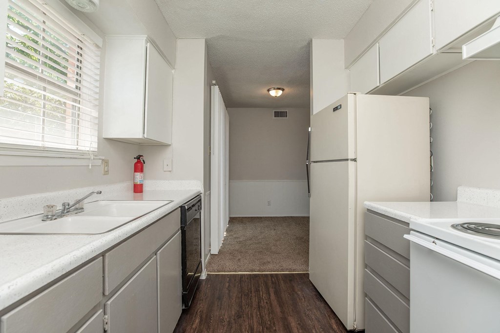 an empty kitchen with white cabinets and a white refrigerator and sink