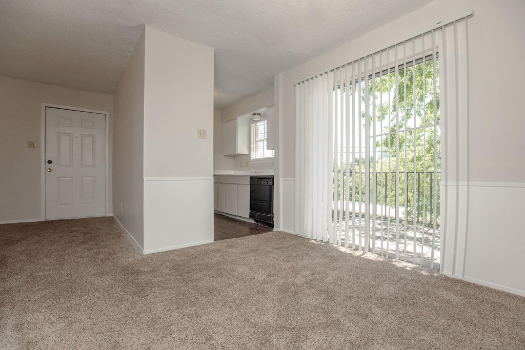 an empty living room with sliding glass doors to a balcony