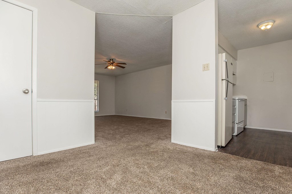 an empty living room with white walls and a ceiling fan