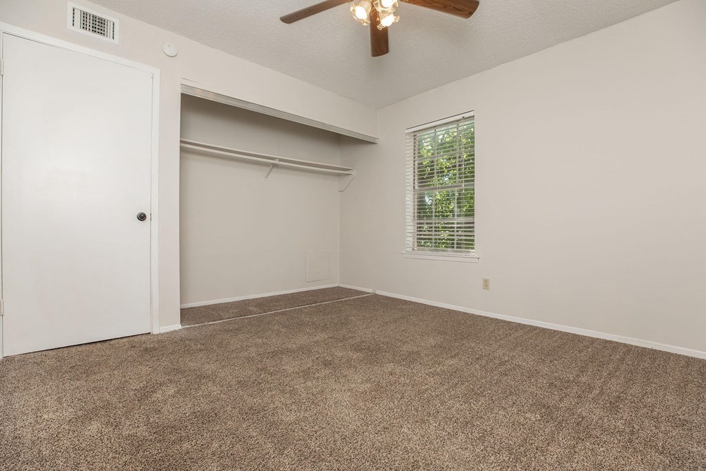 an empty living room with a ceiling fan and a window