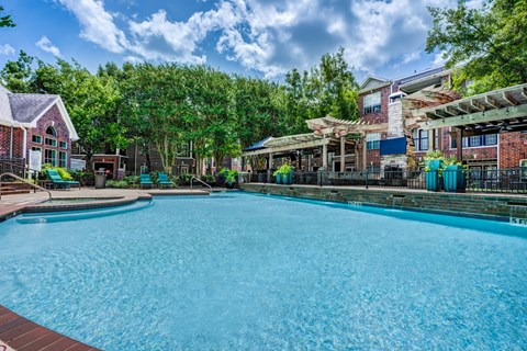 A large swimming pool surrounded by trees and buildings.