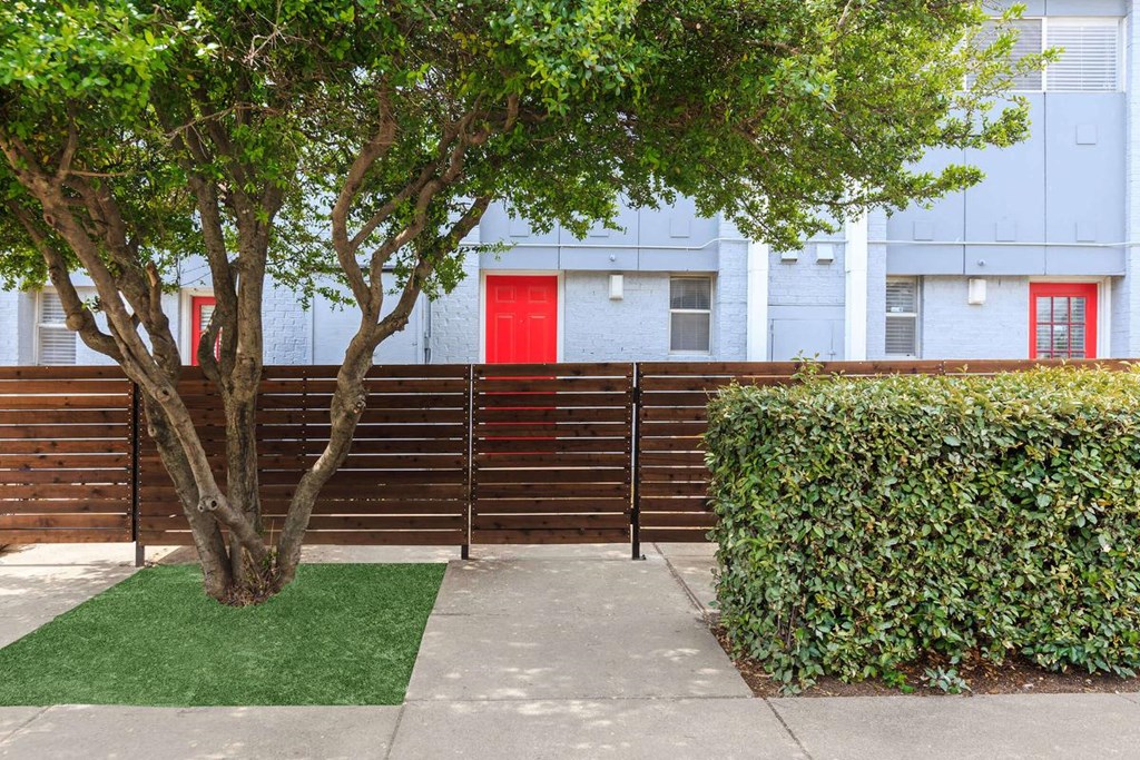a wooden fence in front of an apartment building with a red door