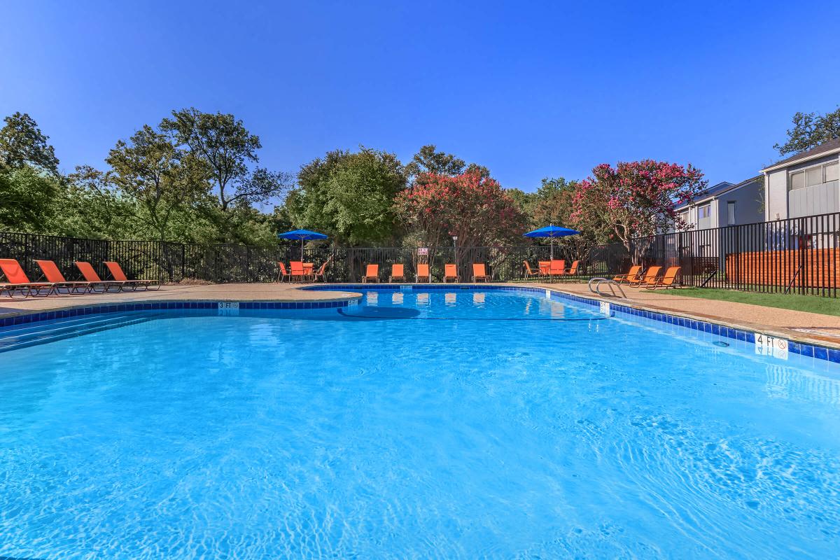 a large swimming pool with chairs and umbrellas in front of a building