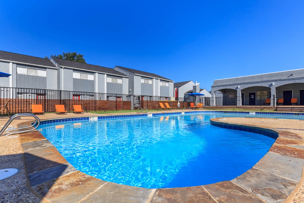 a resort style swimming pool with apartments in the background