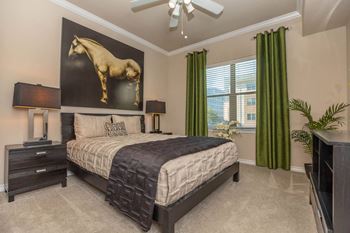 A bedroom with a large bed and a painting of a horse on the wall.
