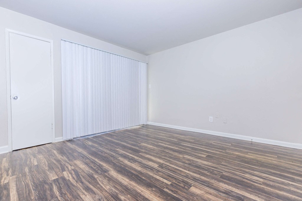 an empty room with wood flooring and white walls and doors
