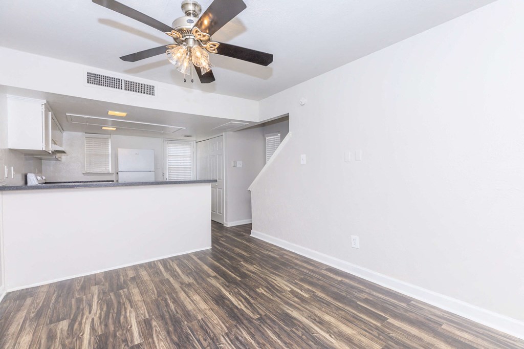 a living room with a ceiling fan and a kitchen