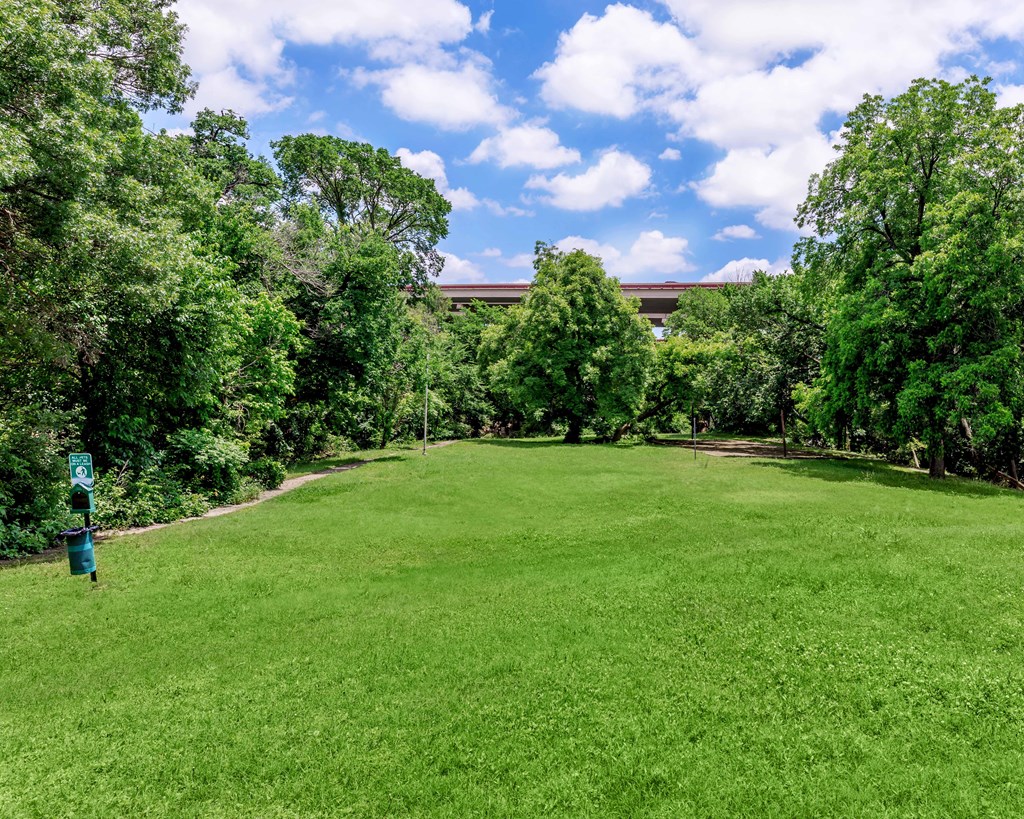 a large grass field with trees and a building in the background