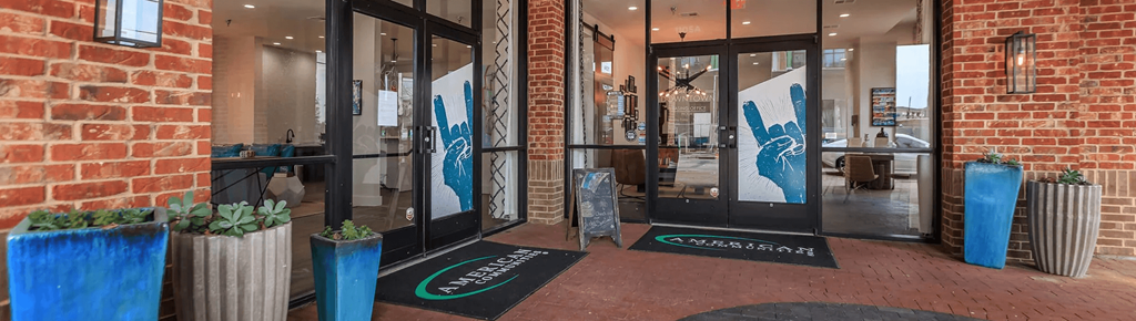 The entrance to a building with a brick wall and glass doors.