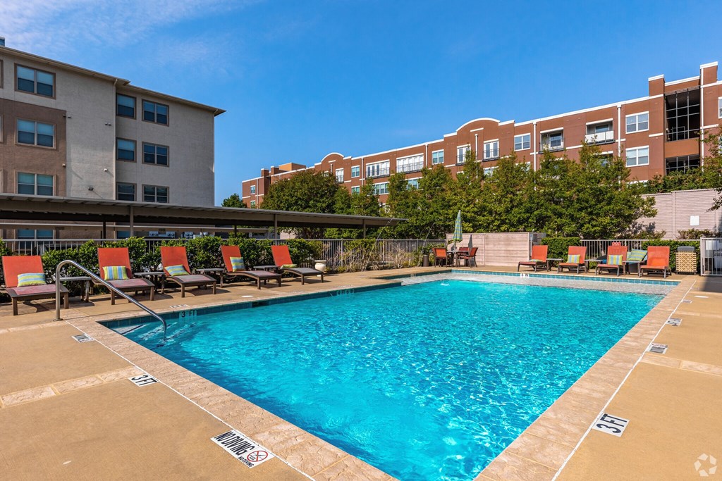 A swimming pool surrounded by chairs and buildings.