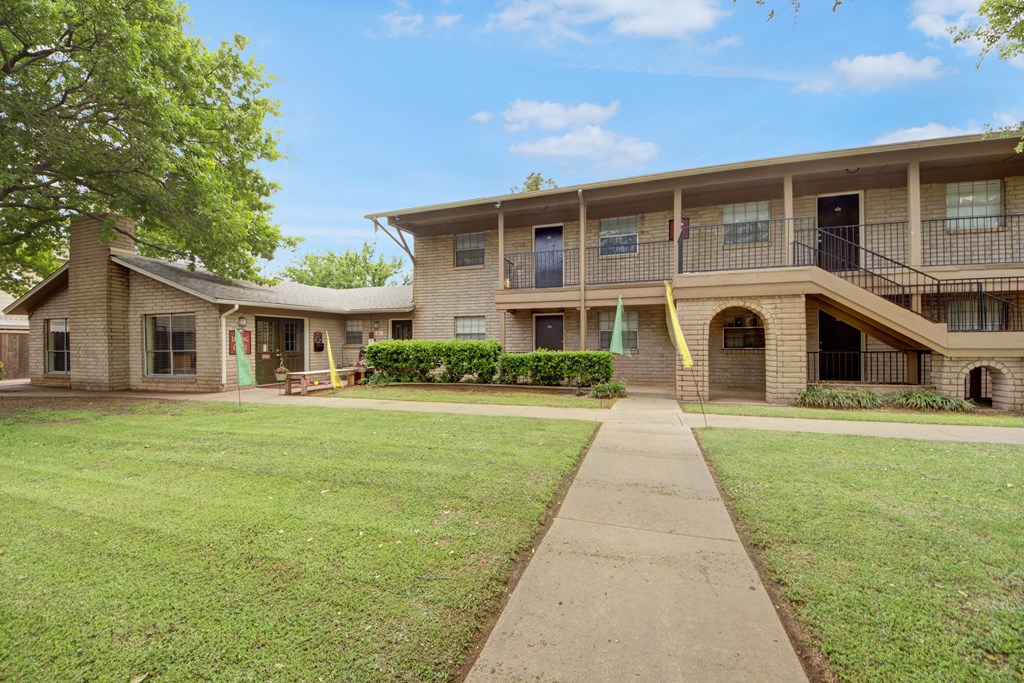 the front of an apartment building with a lawn and sidewalk