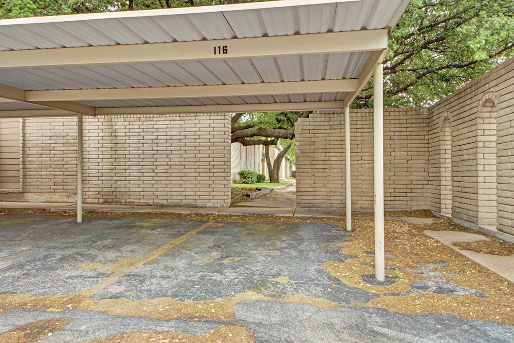 an empty parking lot with a brick building with a porch