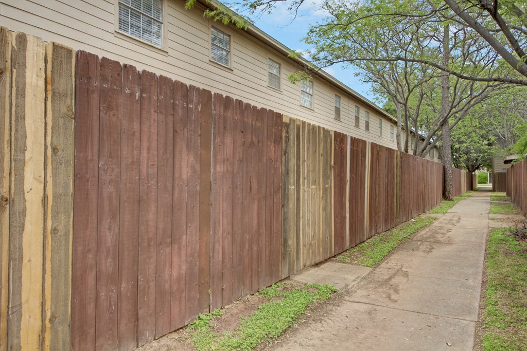 a wooden fence in front of a house with a sidewalk