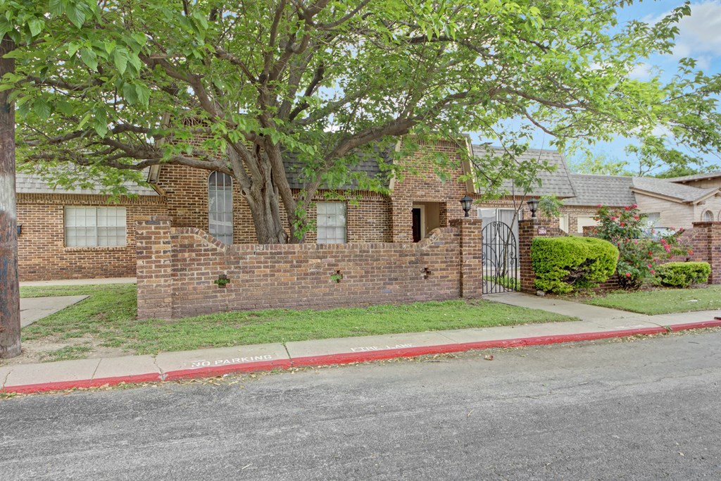 a brick house with a tree and a sidewalk in front of it