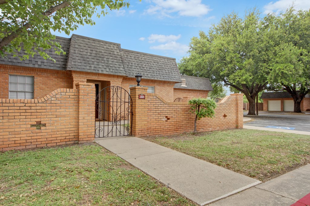 the front of a brick house with a black gate