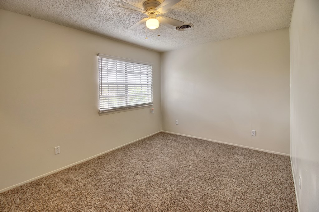 an empty living room with a ceiling fan and a window