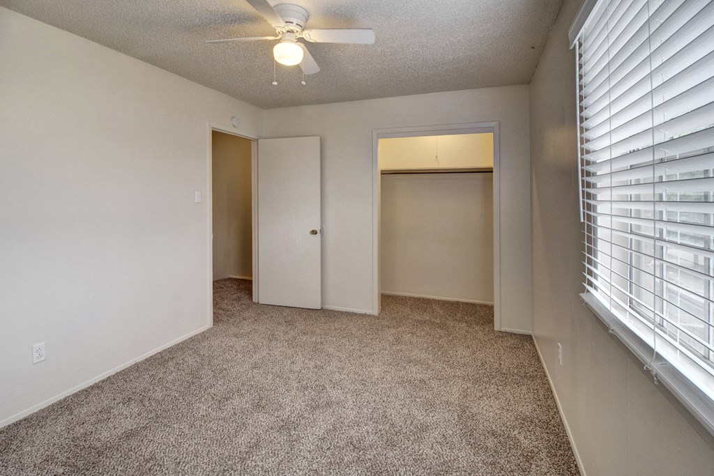 an empty room with a ceiling fan and a window