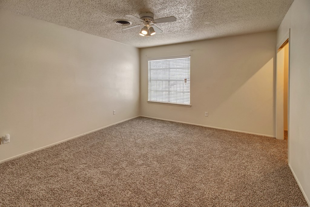 an empty living room with carpet and a ceiling fan