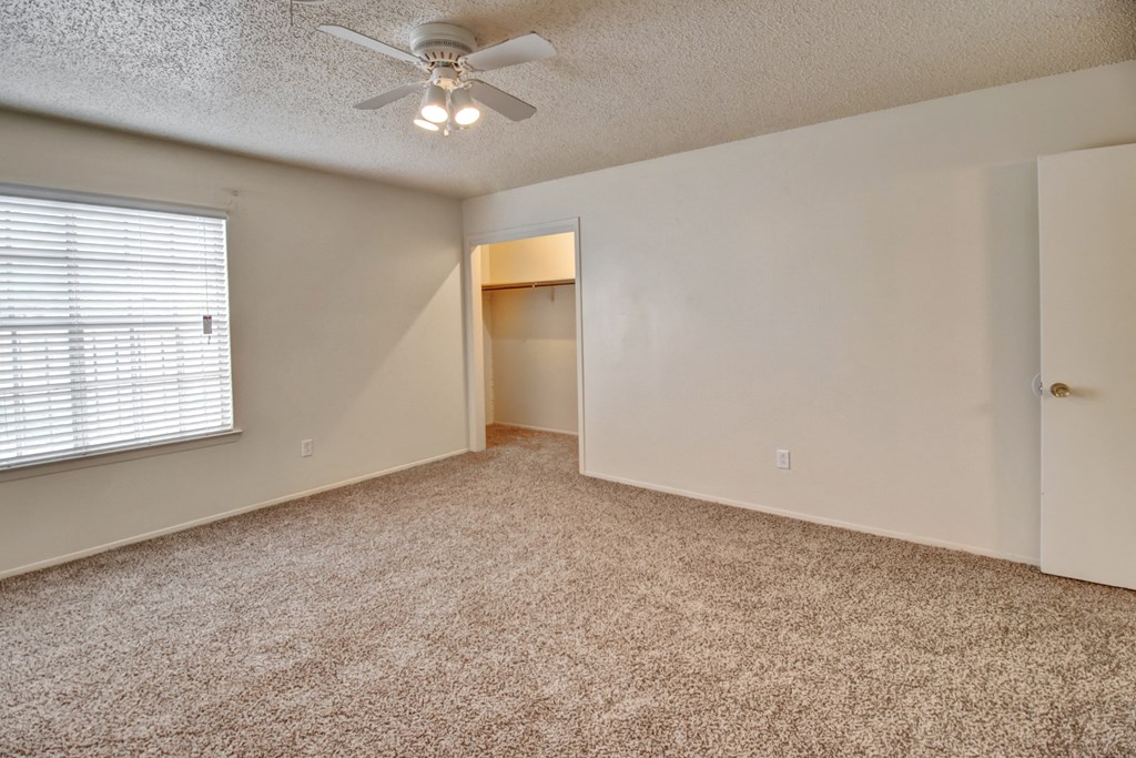 an empty living room with a ceiling fan and a window