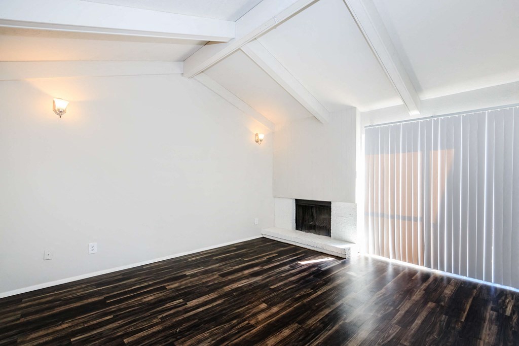 a living room with white walls and wood floors and a fireplace
