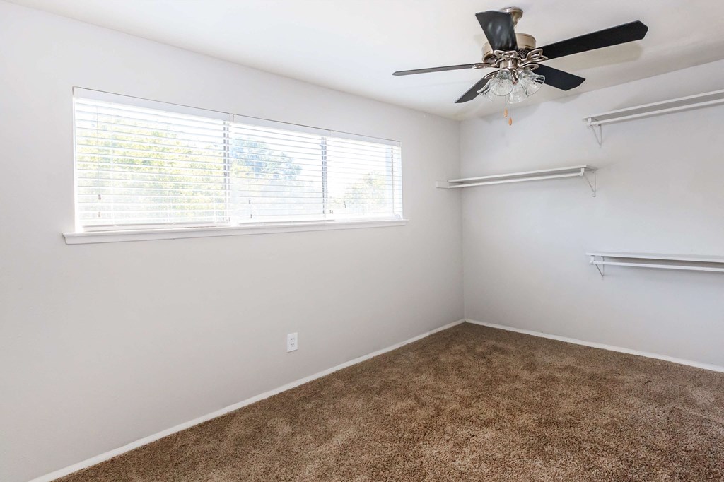 a bedroom with a ceiling fan and a window