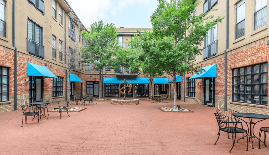 A courtyard with tables and chairs surrounded by brick buildings.