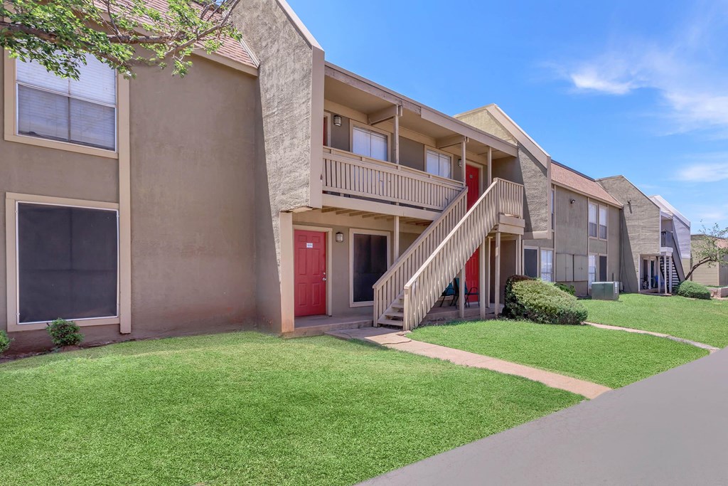 Apartment building with a red door and stairs leading to the entrance.