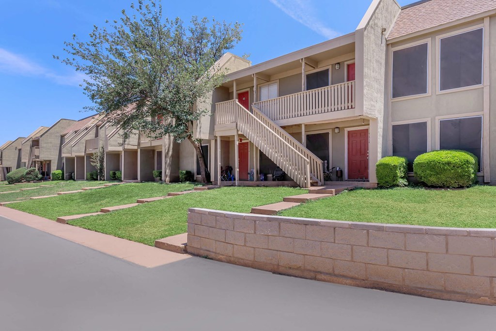 a street view of a row of apartments with grass and trees